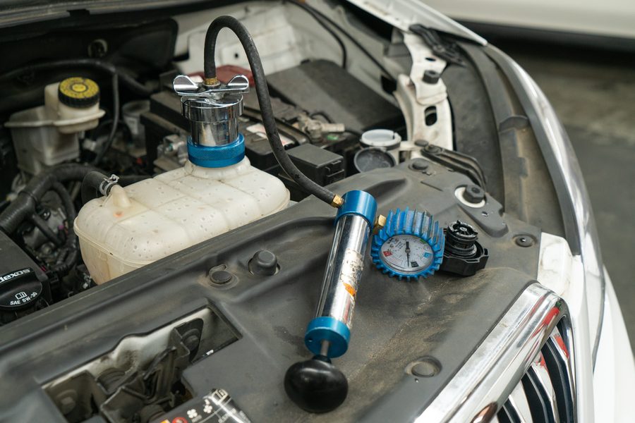 Cooling system pressure tester connected to a vehicle's coolant reservoir