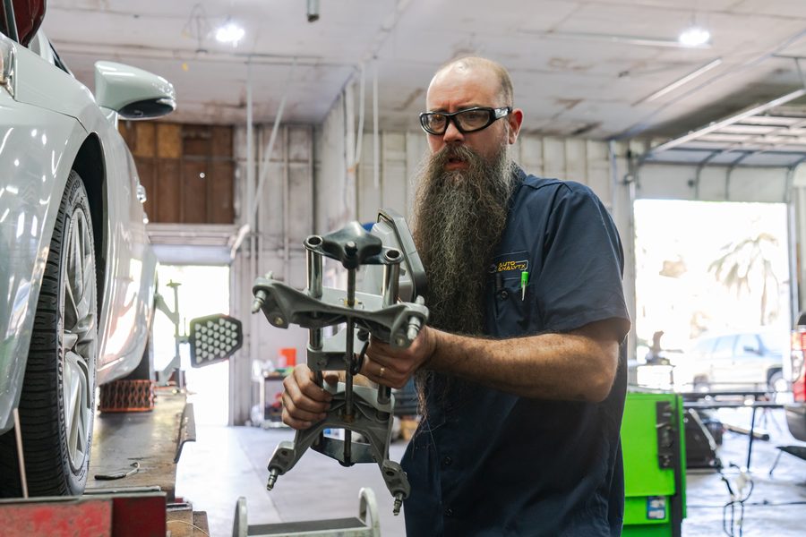 Auto Analytx technician holding a control arm assembly in the workshop